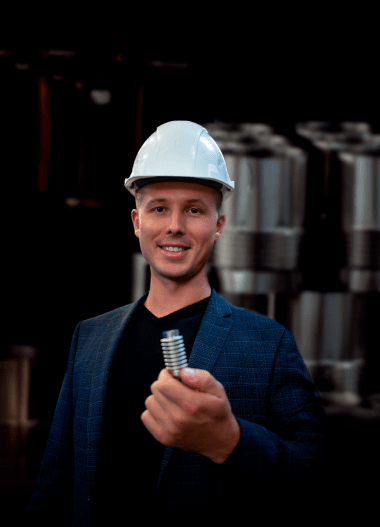 Мужчина в белой каске, показывающий коменсатор в руке